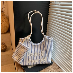 Detail of blue and white striped canvas tote bag with matching pouch on a wooden table