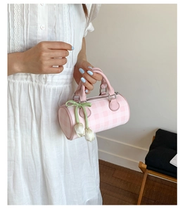 Détail du sac cylindre à damier rose avec pendentif tulipe et nœud vert élégant