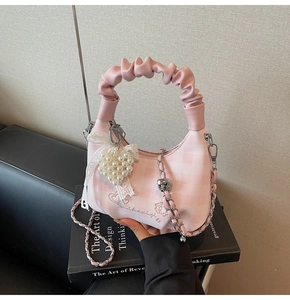 Pink checkered dumpling bag featuring a ruffled handle, pearl heart charm and lace bow