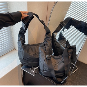 Detail view of two black nylon crossbody bags in different sizes with adjustable straps