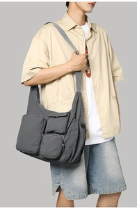 Detail of dark grey nylon messenger bag with multiple functional pockets and wide strap
