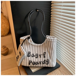 Detail of striped canvas tote bag with black leather straps and mini zipper pouch