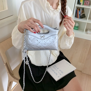 Detailansicht der silbernen Stepptasche mit Strass-Schleifenschnalle und Metallkette