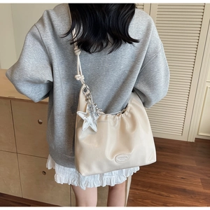 Détail du sac bandoulière plissé crème avec pendentif étoile et bandoulière nouée