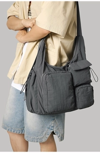 Detail view of charcoal grey nylon messenger bag with multiple utility pockets