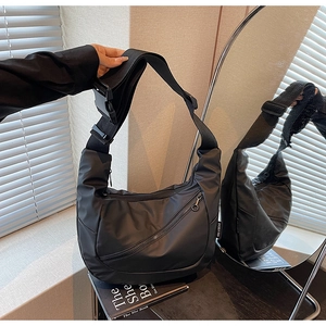 Detail of black waterproof nylon crossbody bag with diagonal zipper and buckle strap