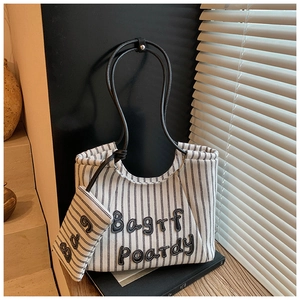 Close-up of black and white striped canvas tote bag with 3D letters and matching mini pouch