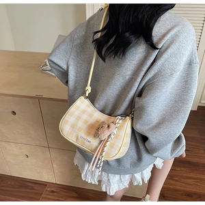 Detailed view of yellow plaid shoulder bag with plush bear charm and ribbon accent