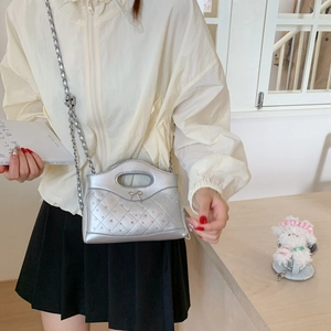 Detailansicht der silbernen Stepptasche mit Metallkette und Schleife am Model