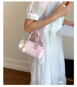 Vue détaillée d'un sac cylindre à carreaux roses avec breloque tulipe et fine bandoulière