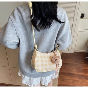 Detail of yellow checkered crossbody bag with adjustable strap and cute bear charm