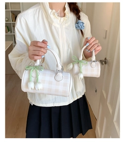 Détail du sac cylindrique à damier avec nœud vert et pendentif tulipe décoratif