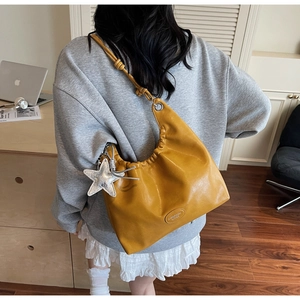 Détail du sac hobo jaune en similicuir souple avec charm étoile et bandoulière nouée