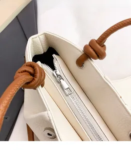 Detailed macro view of silver metal zipper and brown knotted leather strap on tote bag