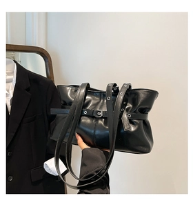Détail d'un sac cabas en cuir noir brillant avec design plissé et sangle à boucle