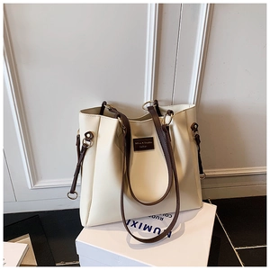 Dettaglio della borsa tote bianco crema con manici marroni ed eleganti anelli dorati