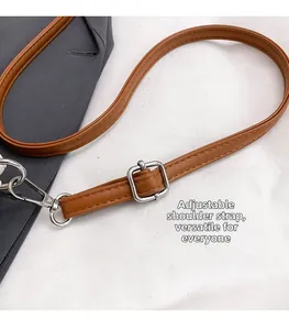Close-up of adjustable brown leather shoulder strap with silver buckle and stitching