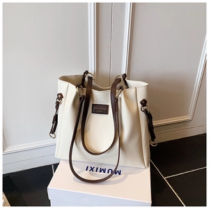 Vista dettagliata della borsa tote in pelle crema con manici marroni e toppa logo