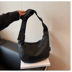 Detail of black nylon crescent shoulder bag with adjustable strap and brand woven label