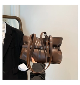 Gros plan détaillé du sac cabas en cuir marron avec œillets métalliques et plis chics