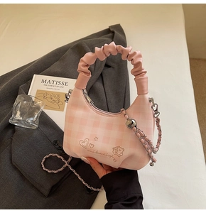Detail of pink plaid handbag featuring ruffled handle and heart star embroidery