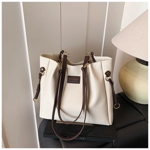 Dettaglio della borsa tote color crema con spalline marroni e fibbie metalliche tonde