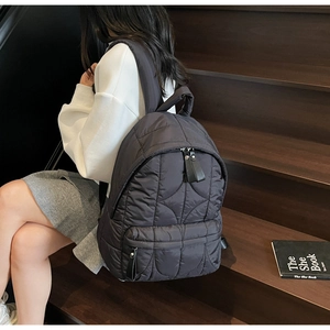 Close-up of black quilted nylon backpack featuring durable wavy stitching and zipper details