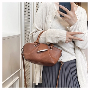Detail of brown lychee-pattern leather bag with shuttle-shaped silver metal clasp
