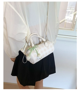 Detail of checkered barrel crossbody bag with green bow and tulip pendant on model