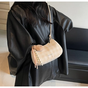 Detail of off-white checkered hobo bag with plush charm on a model in a leather jacket