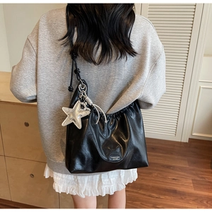 Détail du sac cabas en cuir noir avec pendentif étoile de mer argentée et logo sur un mannequin
