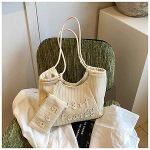 Detail of canvas tote bag with yellow stripes and textured 3D embroidery on a vintage chair