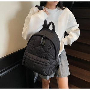 Detail of black quilted nylon backpack featuring large main compartment and front pocket