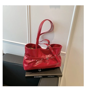 Détail d'un sac cabas rouge avec boucle décorative sur un canapé en cuir noir élégant