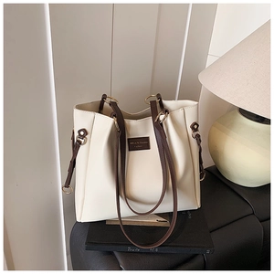 Dettaglio della borsa tote in pelle crema con cinturini marroni e etichetta del marchio