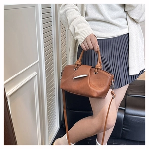 Close-up of brown lychee pattern leather handbag with silver metallic fang magnetic clasp