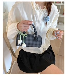 Détail d'un sac cylindrique à carreaux avec pendentif tulipe et poignées noires