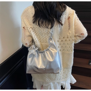Détail d'un sac hobo argenté métallisé avec texture plissée et breloque étoile sur l'épaule