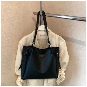 Dettaglio borsa tote in pelle PU opaca nera con fibbie dorate e toppa del marchio