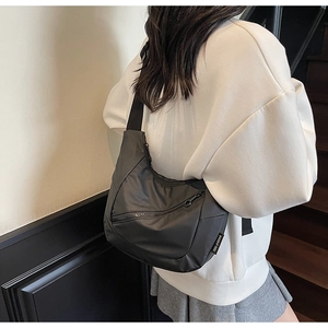 Detail of black crescent crossbody bag showing high-density nylon texture and zipper pocket