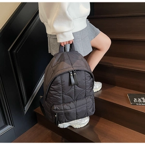 Close-up of quilted nylon backpack featuring wave stitching and premium leather zipper pulls