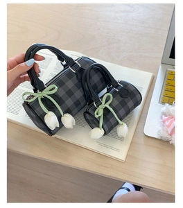 Détail du sac cylindre à carreaux avec ruban vert et pendentif tulipe élégant