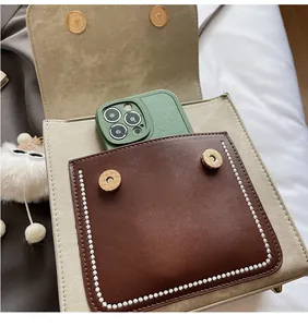 Detail of canvas and leather shoulder bag featuring a magnetic buckle and front pocket