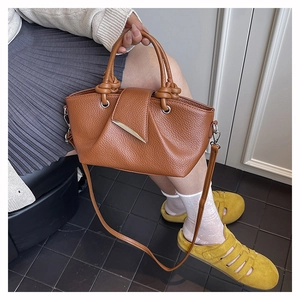 Detail of a brown lychee pattern leather tote bag with knotted handle and silver hardware