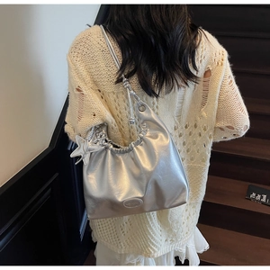 Détail du sac hobo argenté métallisé avec plis et pendentif étoile porté par le modèle