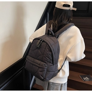 Detail of dark grey quilted nylon backpack with padded texture and leather zipper pulls