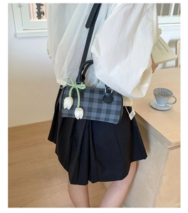 Macro side view of plaid cylinder crossbody bag with decorative tulip and ribbon