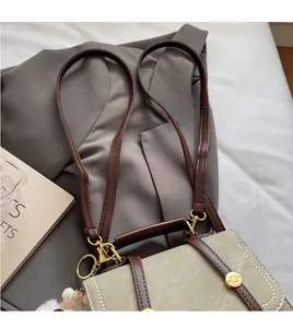 Detail of adjustable long shoulder strap and golden metal hardware on contrast canvas bag