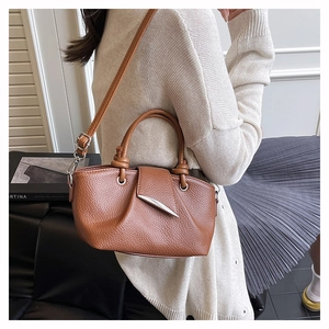 Detail of brown lychee grain leather tote with cylindrical handle and silver leaf buckle