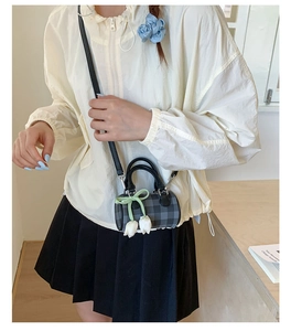 Détail du mini sac cylindre à carreaux avec ruban vert et breloque fleur tulipe